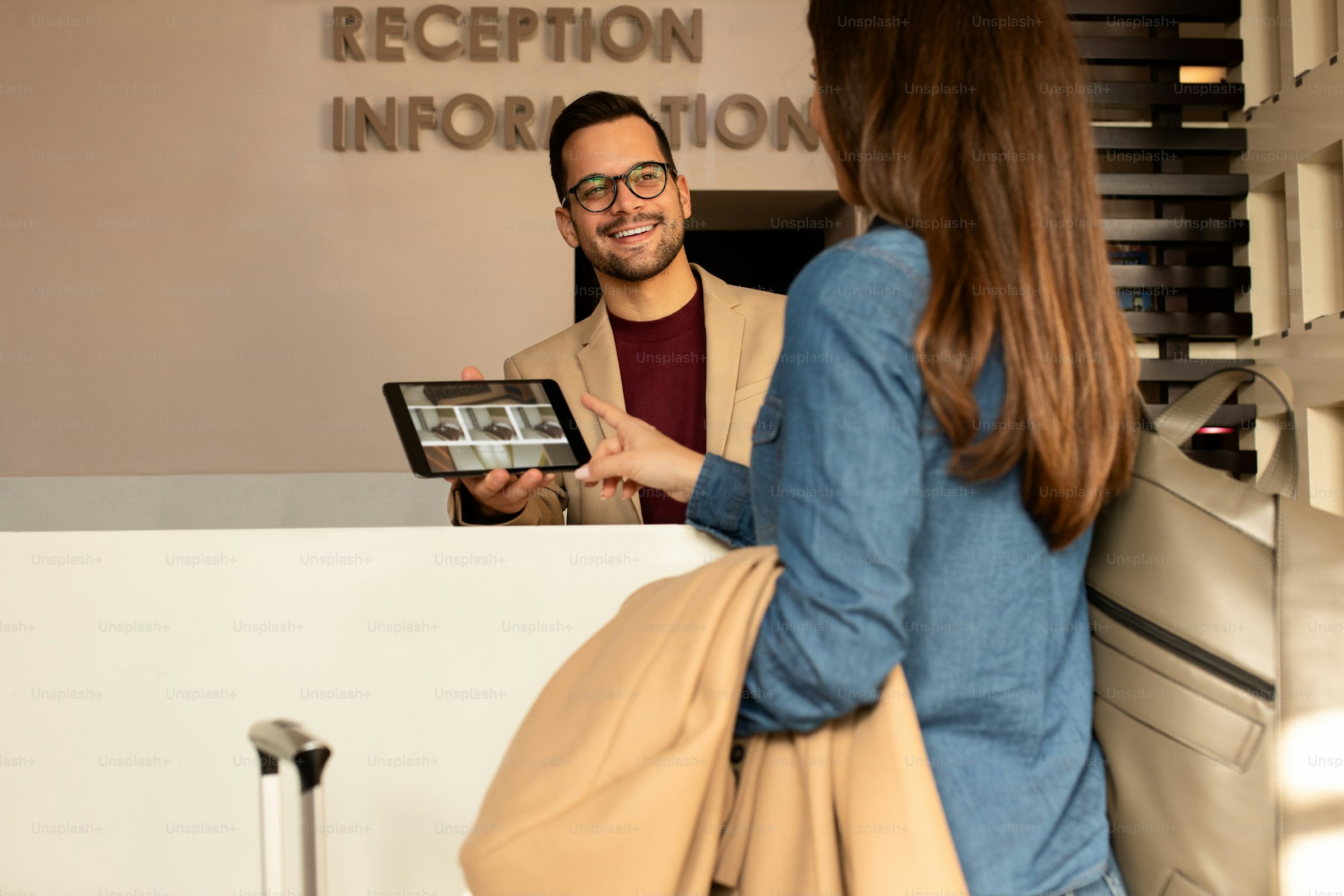 Front-desk staff checking in a guest at a hotel counter